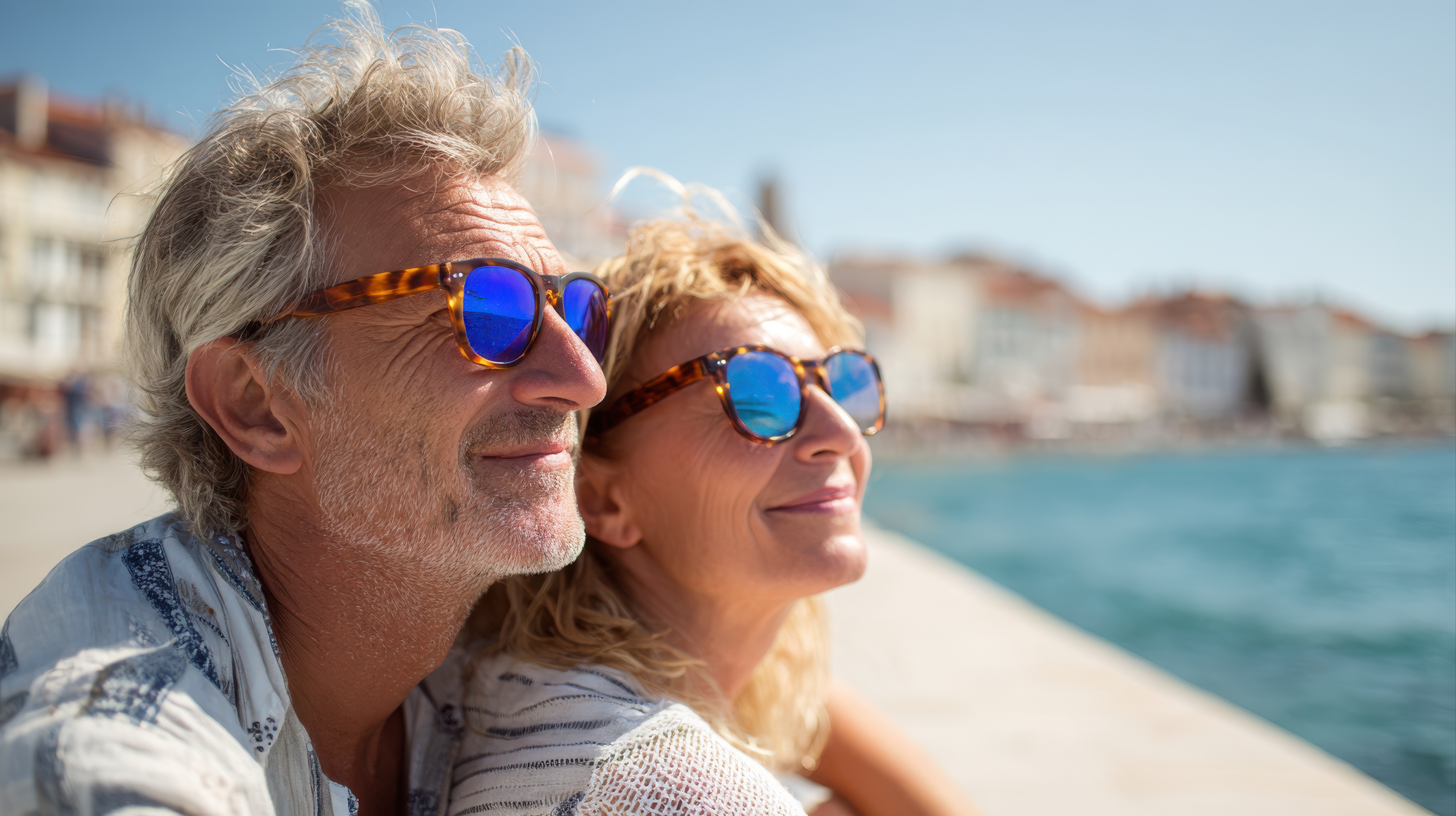 A retired couple smiling together by the coast, enjoying their retirement
